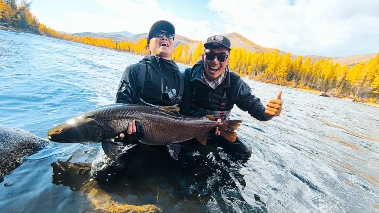 Anglers holding a taimen beside a Mongolian river