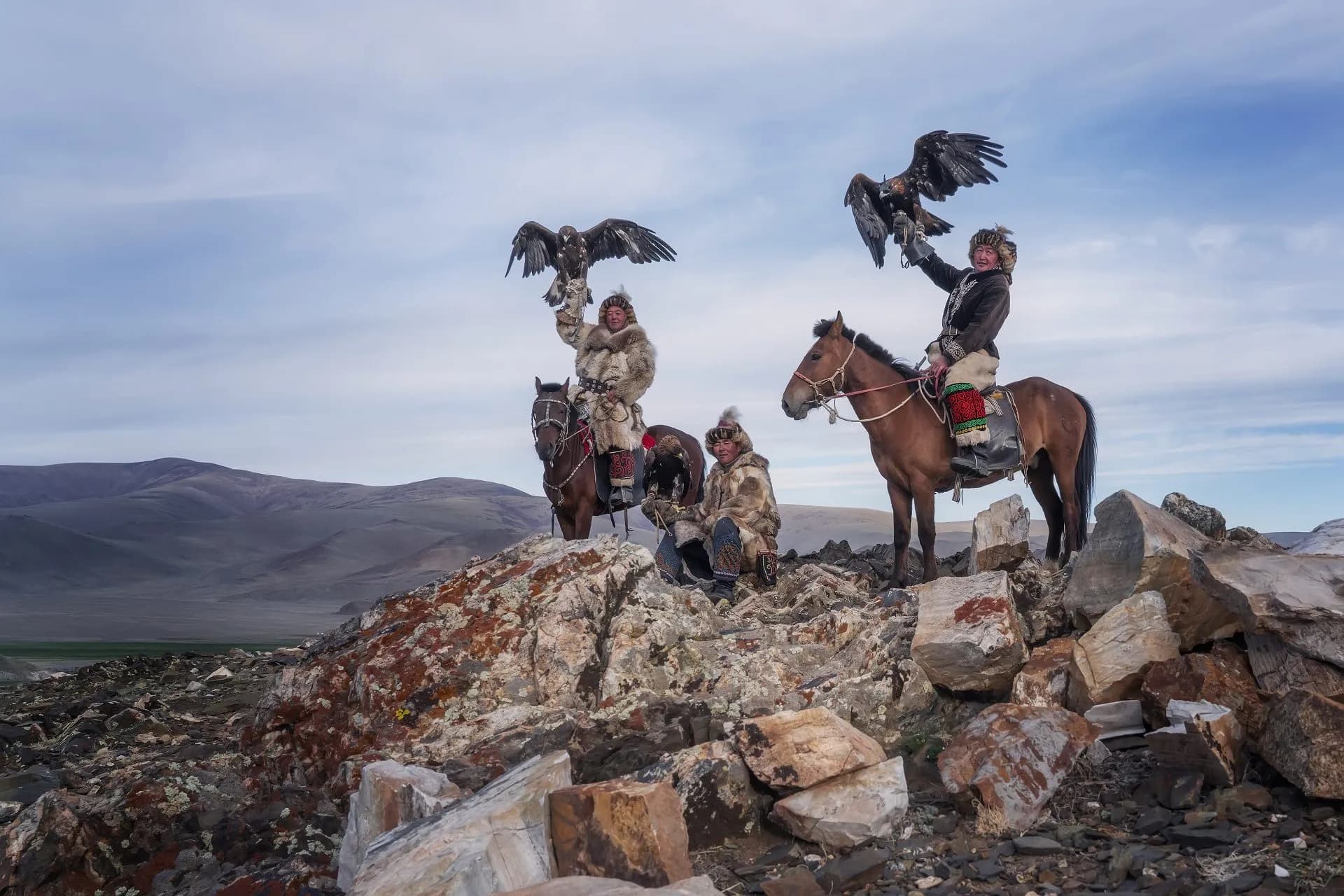Kazakh eagle hunters standing on a mountain ridge in Bayan-Ölgii