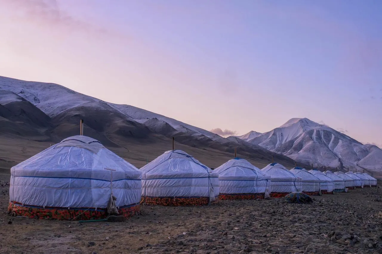 Seasonal ger camp beneath Tsambagarav Mountain at sunset
